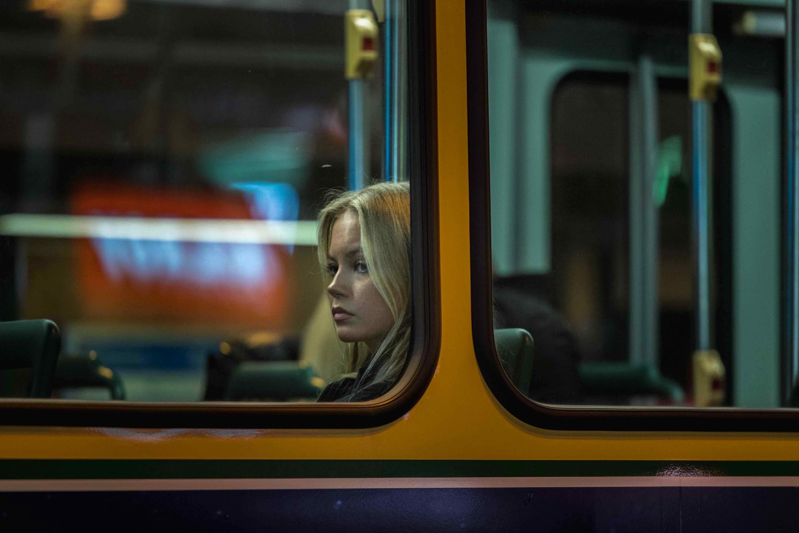 Woman glancing sideways, lit through a train window at night